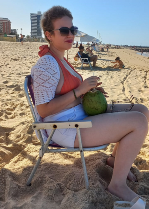 mulher sentada na areia da praia